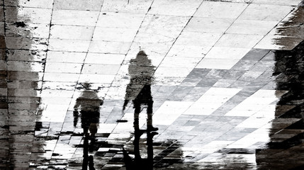 Blurry reflection shadow of two people on a rainy day