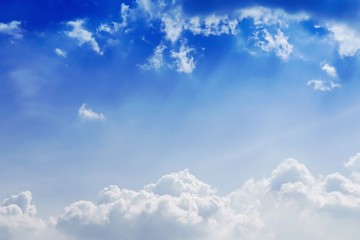 Blue sky background with puffy white clouds and sunlight.
