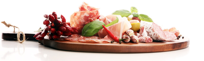 Food tray with delicious salami, pieces of sliced prosciutto crudo, sausage and basil. Meat platter with selection