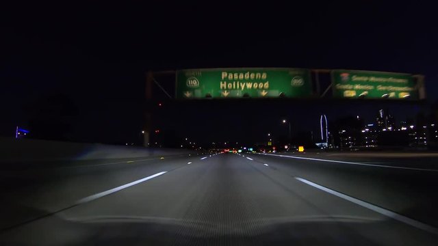 Night driving view of the Hollywood and Pasadena 110 overhead highway sign on the Harbor freeway in downtown Los Angeles, California.   