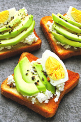 Appetizing avocado toasts with curd and egg.
