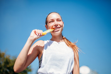 young athletic woman holding a protein bar in her teeth. Healthy lifestyle concept