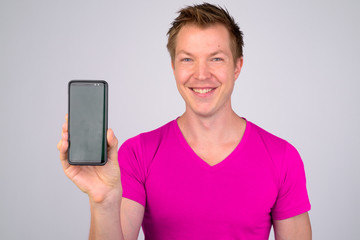 Face of happy young handsome man smiling while showing phone