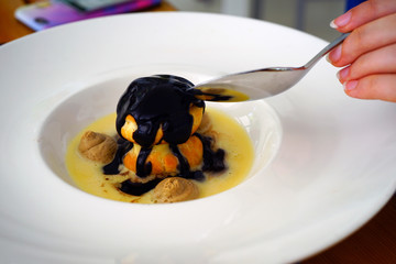View of a profiterole, a French choux pastry filled with ice cream and chocolate sauce