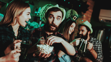Man In Funny Hat Is Eating Popcorn With A Girl.