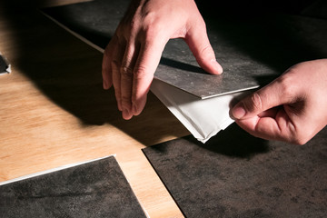 Fototapeta na wymiar Removing backing from peel and stick vinyl flooring tiles.