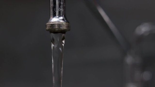 Closeup view of faucet running tap water, turned off and slowly drying up to a drip.