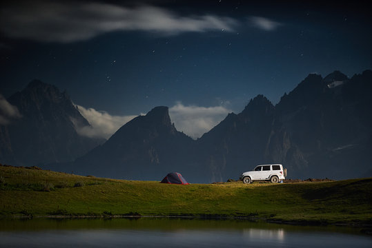Camping with a car, tent at night with moonlight at mountain range