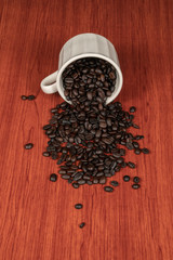Coffee beans in white cup with wooden background