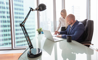 A man and a woman in business suits in the workplace in a skyscraper overlooking a large modern metropolis, business and success, solving business issues