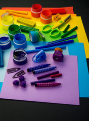 School accessories are laid out in the form of a rainbow. Black background.