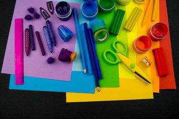 School accessories are laid out in the form of a rainbow. Black background.