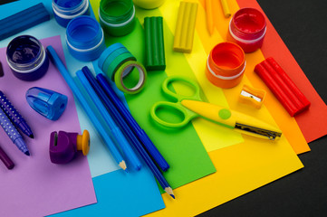 School accessories are laid out in the form of a rainbow. Black background.