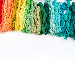 Rainbow color threads for embroidery on a white background.
