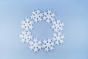 A wreath in a circle of decorative snowflakes on a blue background.