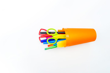 Pencils and felt-tip pens in a plastic cup on a white background.