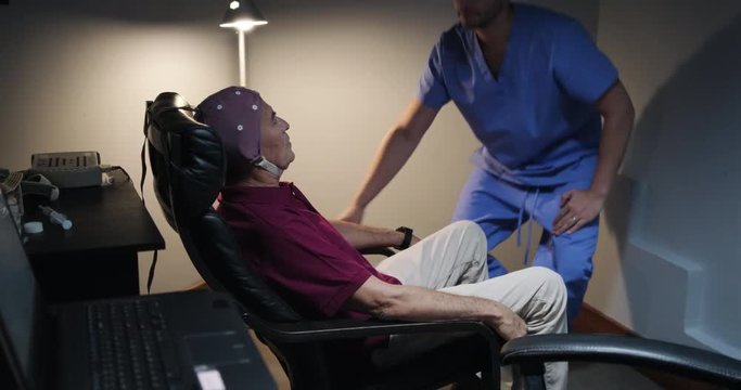 Nurse in Geriatric Clinic Performs an EEG on Senior Patient