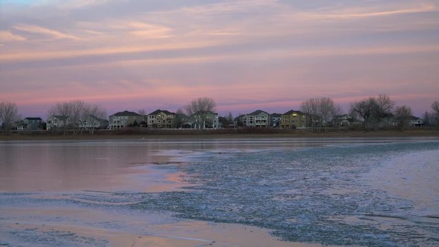 Lake freezing after winter sunset with a residential houses - Boyd Lake State Park in Colorado