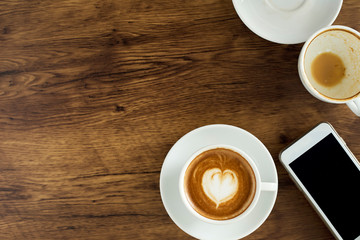 Smart phone with latte art coffee on wooden background