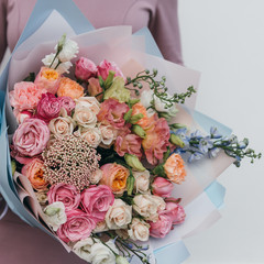 Colorful bouquet of different fresh flowers in the hands of a florist woman. Rustic flower background. Craft bouquet of flowers.