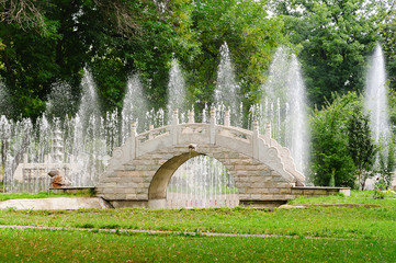 beautiful stone bridge in traditional chinese park on background of fountains. summer landscape