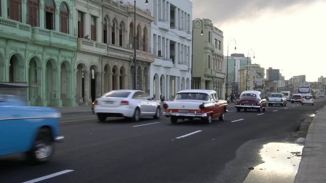 Row of 1950's American vintage classic cars driving on waterfront malecon street in old Havana, Cuba