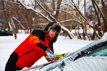 Teenager to clean the car from snow in winter