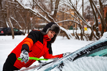 Teenager to clean the car from snow in winter