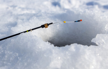 Fishing rod near the hole in the ice