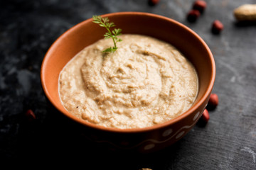 Healthy Peanut chutney made using Groundnut / Shengdana or mungfali. served in a small bowl with raw whole. Selective focus