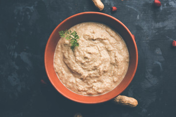 Healthy Peanut chutney made using Groundnut / Shengdana or mungfali. served in a small bowl with raw whole. Selective focus