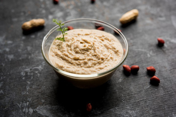 Healthy Peanut chutney made using Groundnut / Shengdana or mungfali. served in a small bowl with raw whole. Selective focus