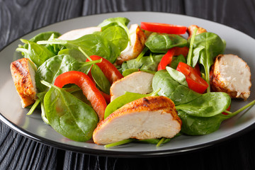 Close up of a dietary salad of fresh baby spinach, chicken breast and bell pepper on a plate. horizontal