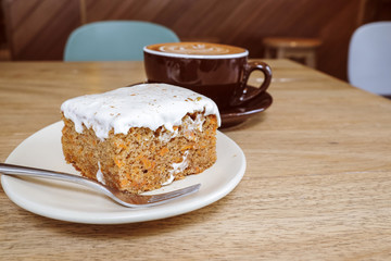 Hot Latte Coffee with Carrot Cheesecake on Wooden Table