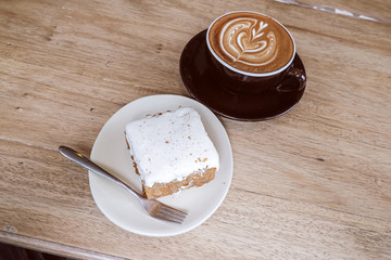 Hot Latte Coffee with Carrot Cheesecake on Wooden Table