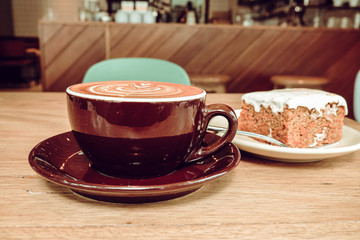 Hot Latte Coffee with Carrot Cheesecake on Wooden Table
