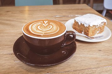 Hot Latte Coffee with Carrot Cheesecake on Wooden Table