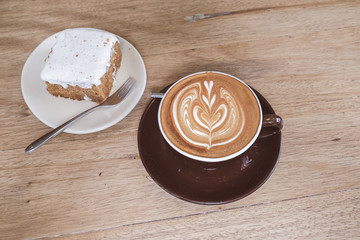 Hot Latte Coffee with Carrot Cheesecake on Wooden Table