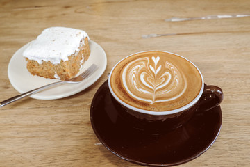 Hot Latte Coffee with Carrot Cheesecake on Wooden Table