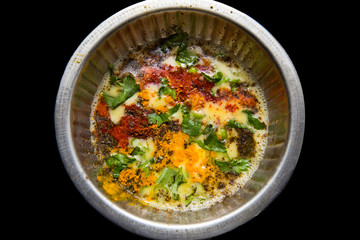 Beaten up egg yolk with raw spices turmeric powder, red chili powder, black pepper powder, coriander leaves
