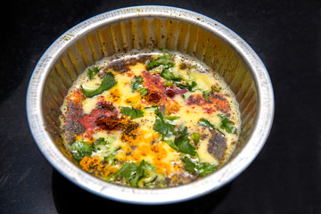 Beaten up egg yolk with raw spices turmeric powder, red chili powder, black pepper powder, coriander leaves