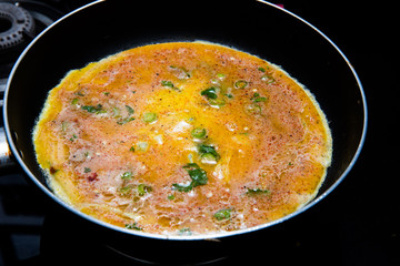 cooking omlette in Indian style with green chili , corriander leaves and lot of spices in a non stick pan