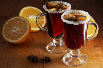 Two cups with ready mulled wine with anise, cinnamon and nuts around	