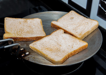 bread being cooked on a flat pan with lot of butter to make crisp toast
