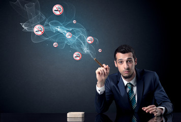 Businessman smoking with floating no smoking signs beside his head.