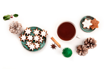Zimtsterne, traditional Christmas cinnamon star cookies, shot from the top on a white background with hot chocolate, spices, a toy Christmas tree, pine cones, and a place for text