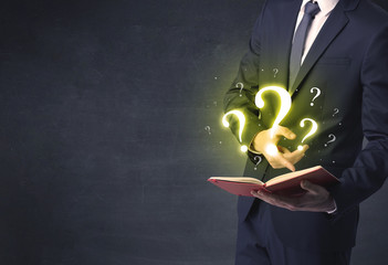 Businessman holding a book with question mark symbol.