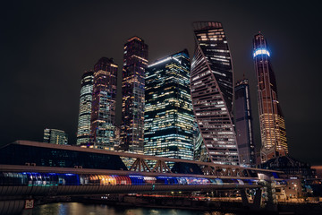 Moscow city night view with skyscrapers and a futuristic bridge over the river