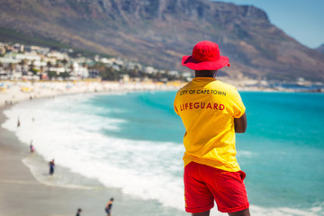 Kapstadt-Rettungsschwimmer, der den berühmten Strand von Camps Bay mit türkisfarbenem Wasser beobachtet