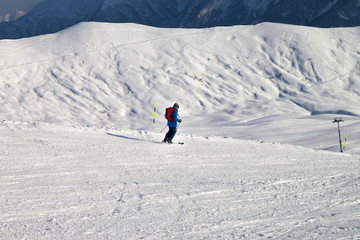 Fototapeta na wymiar Skier downhill on snowy ski slope in sun winter evening